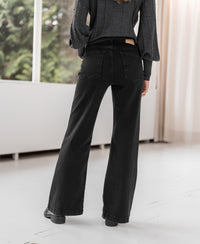 Black denim wide leg jeans, back view, indoors.