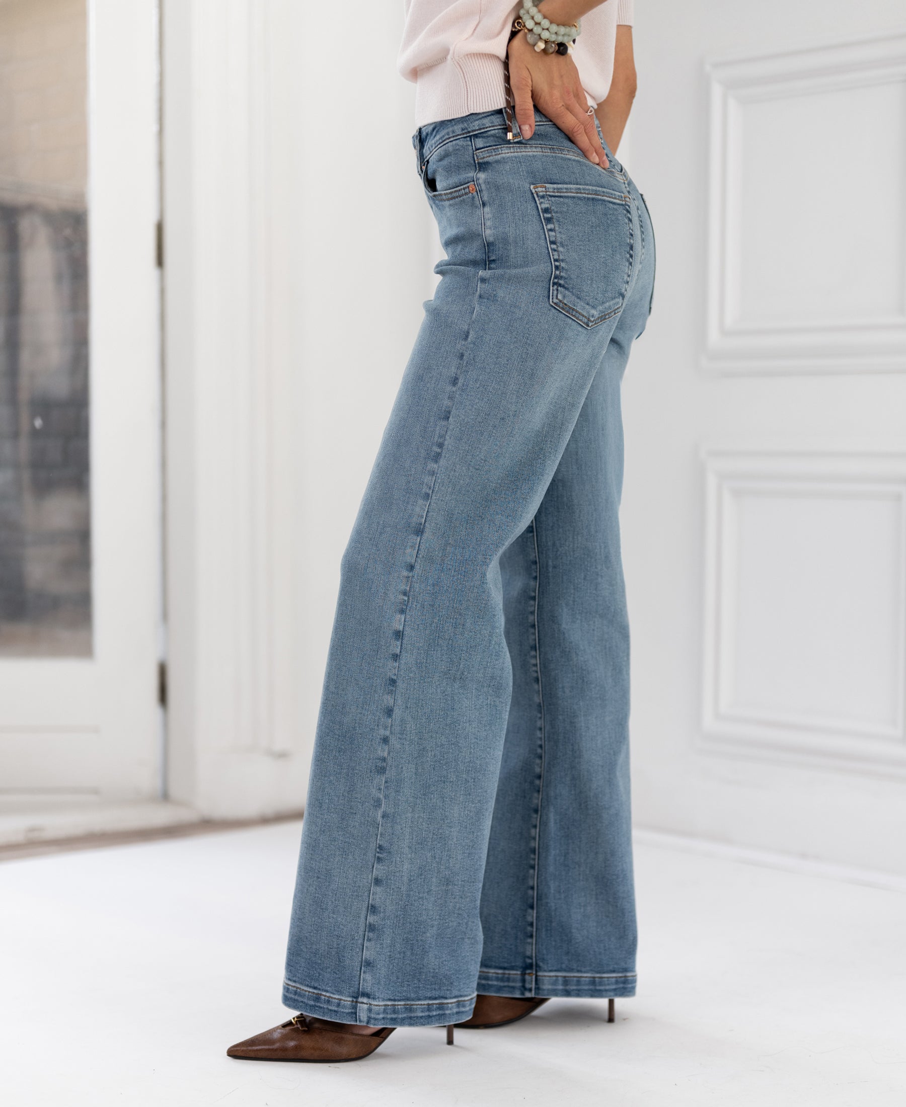 Wide leg light stone jeans in a bright, white-walled room.