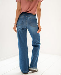 Back view of woman wearing PLEIN PUBLIQUE blue wide-leg jeans.