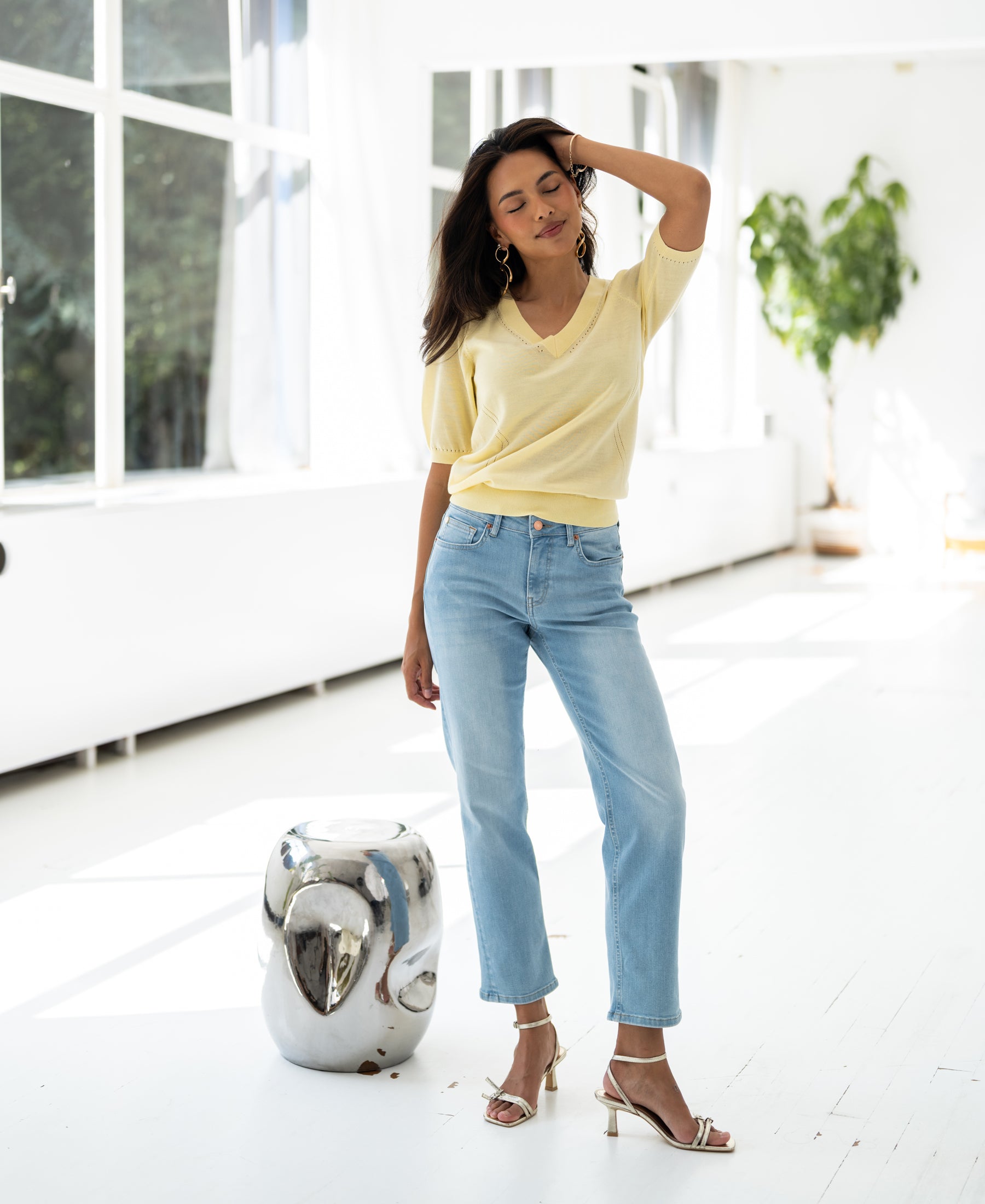 Model wearing yellow LA DIAZ V-neck sweater indoors, sunlight shining.