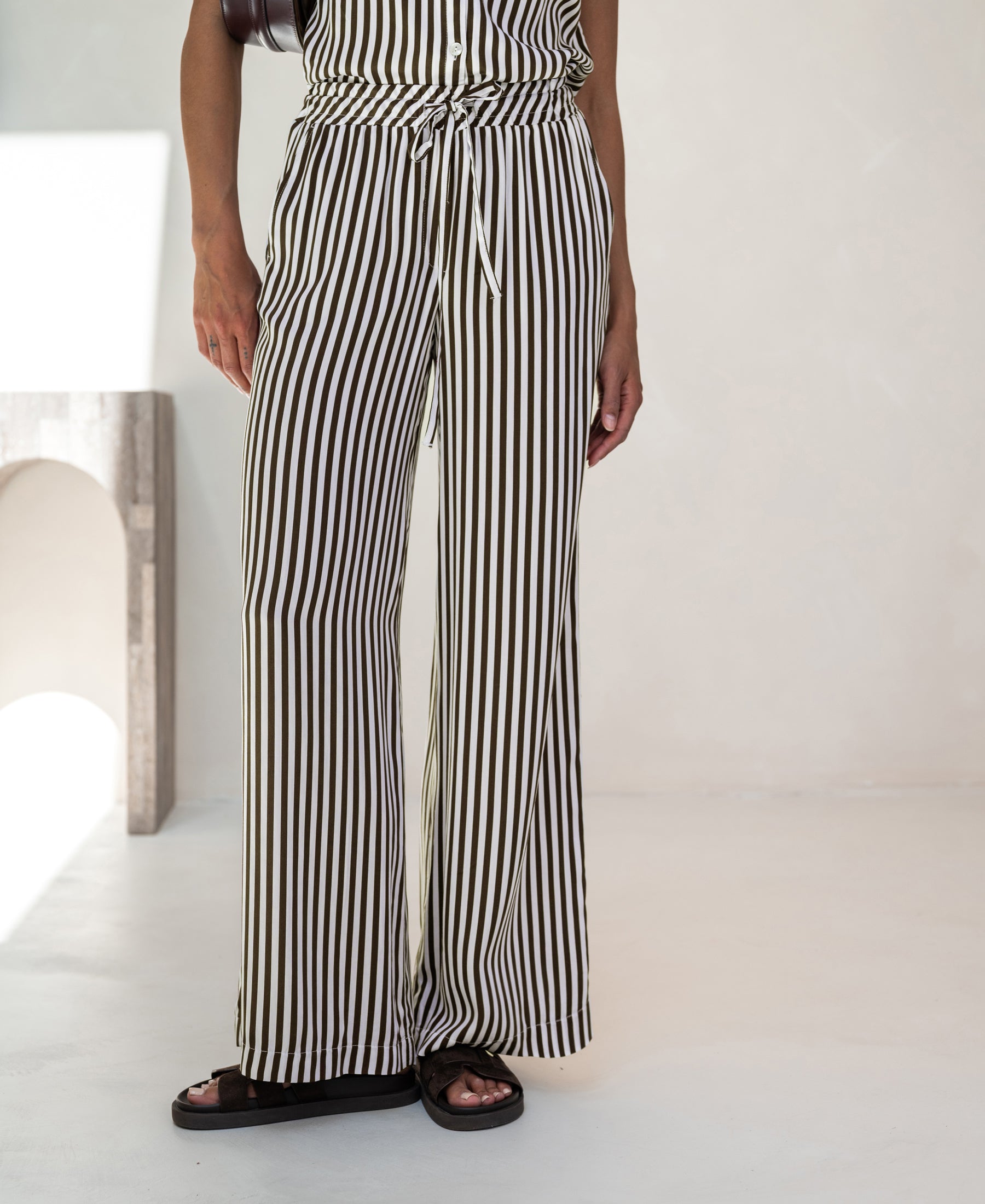 Ivory-cocoa striped summer trousers displayed indoors against a light background.