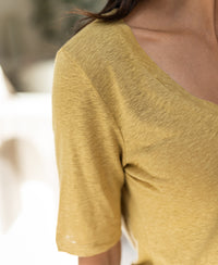 Close-up of the PLEIN PUBLIQUE Linen T-shirt LA DOMI in mustard yellow, showing fabric at neck and shoulder.
