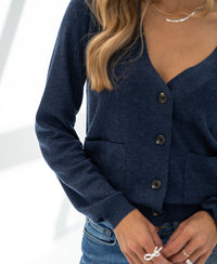 Close-up of a woman wearing the PLEIN PUBLIQUE Merino wool cardigan LA DONNA in indigo blue.