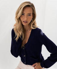 Woman wears a dark blue merino wool vest from PLEIN PUBLIQUE on a white background.