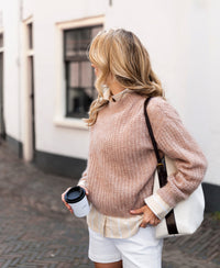 Blonde woman wearing PLEIN PUBLIQUE's mohair sweater in light brown, standing on a city street.