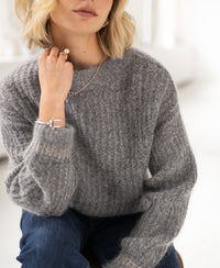 Light grey mélange mohair sweater by PLEIN PUBLIQUE, shown on a woman with a soft blurred background.