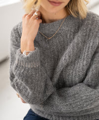 Woman wearing grey melange mohair sweater, facing away.