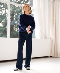 Woman wears navy mohair sweater in a bright room with large windows.
