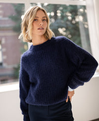 Navy mohair sweater made by PLEIN PUBLIQUE, seen indoors with a window and greenery in the background.
