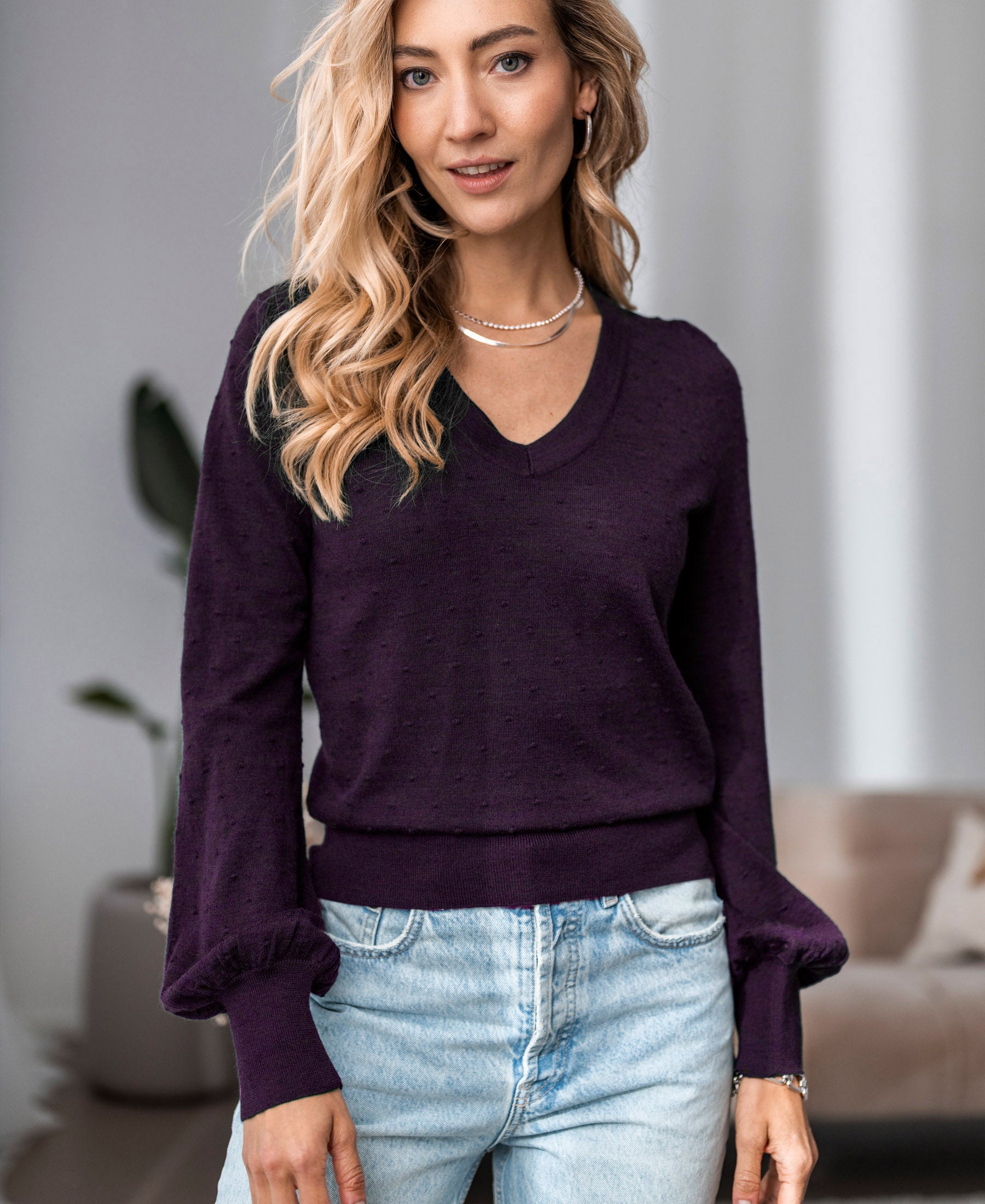 Merino wool V-neck sweater in aubergine from Plein Publique, shown indoors.