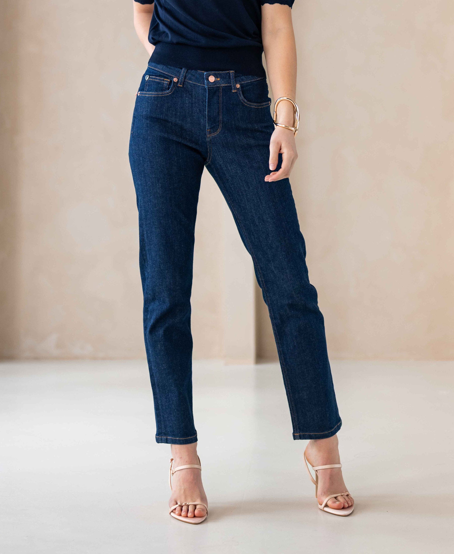 Woman wearing cropped jeans in dark blue rinse wash indoors.