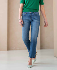 Woman wearing stonewash cropped jeans on a beige background.
