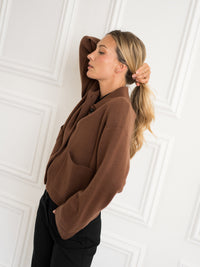 Woman wearing the Plein Publique wool jacket LA FAYE in camel, shown from the side.