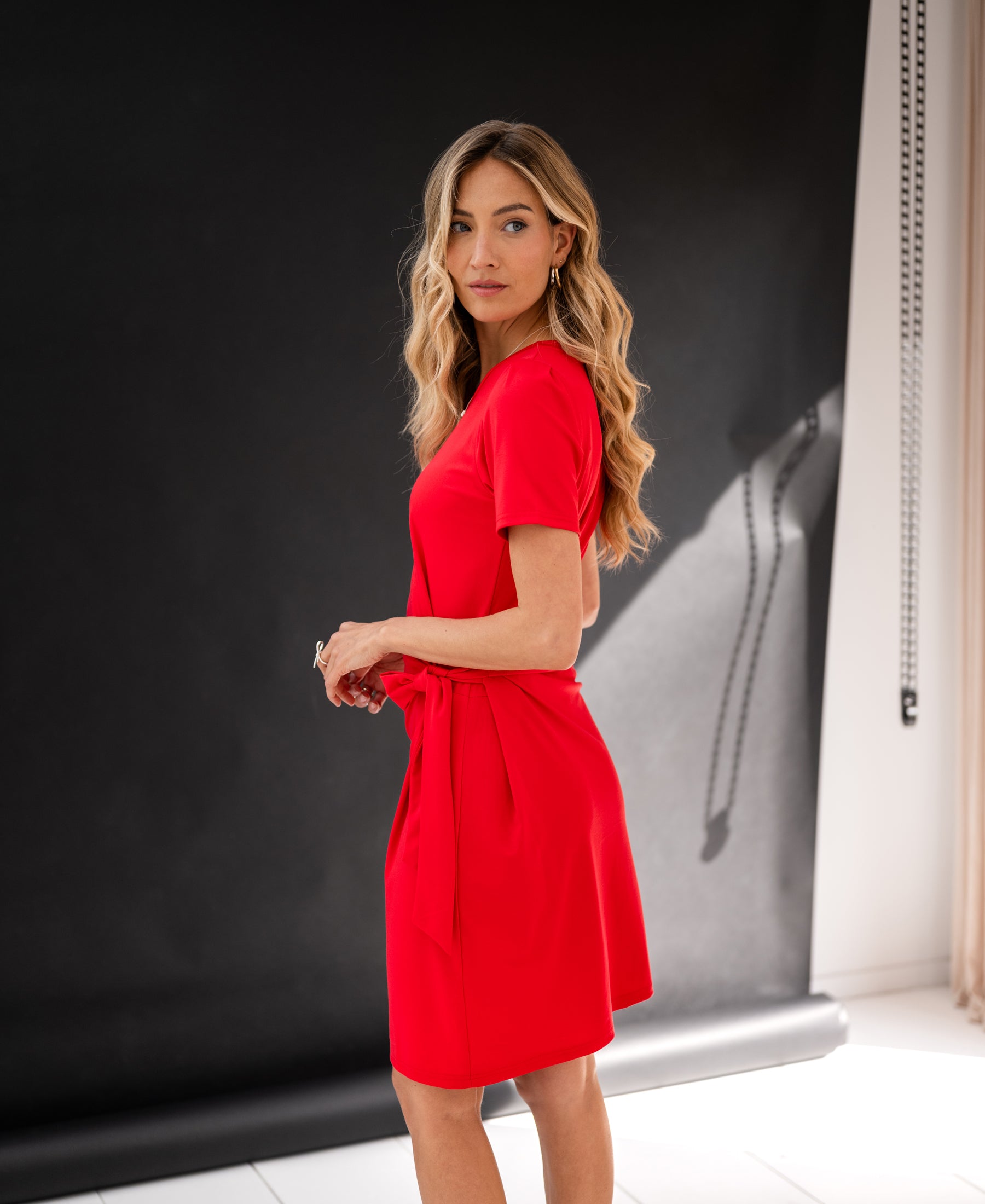 Red button-down dress by PLEIN PUBLIQUE, shown from the side against a black backdrop.