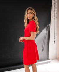 Red button-down dress by PLEIN PUBLIQUE, shown from the side against a black backdrop.