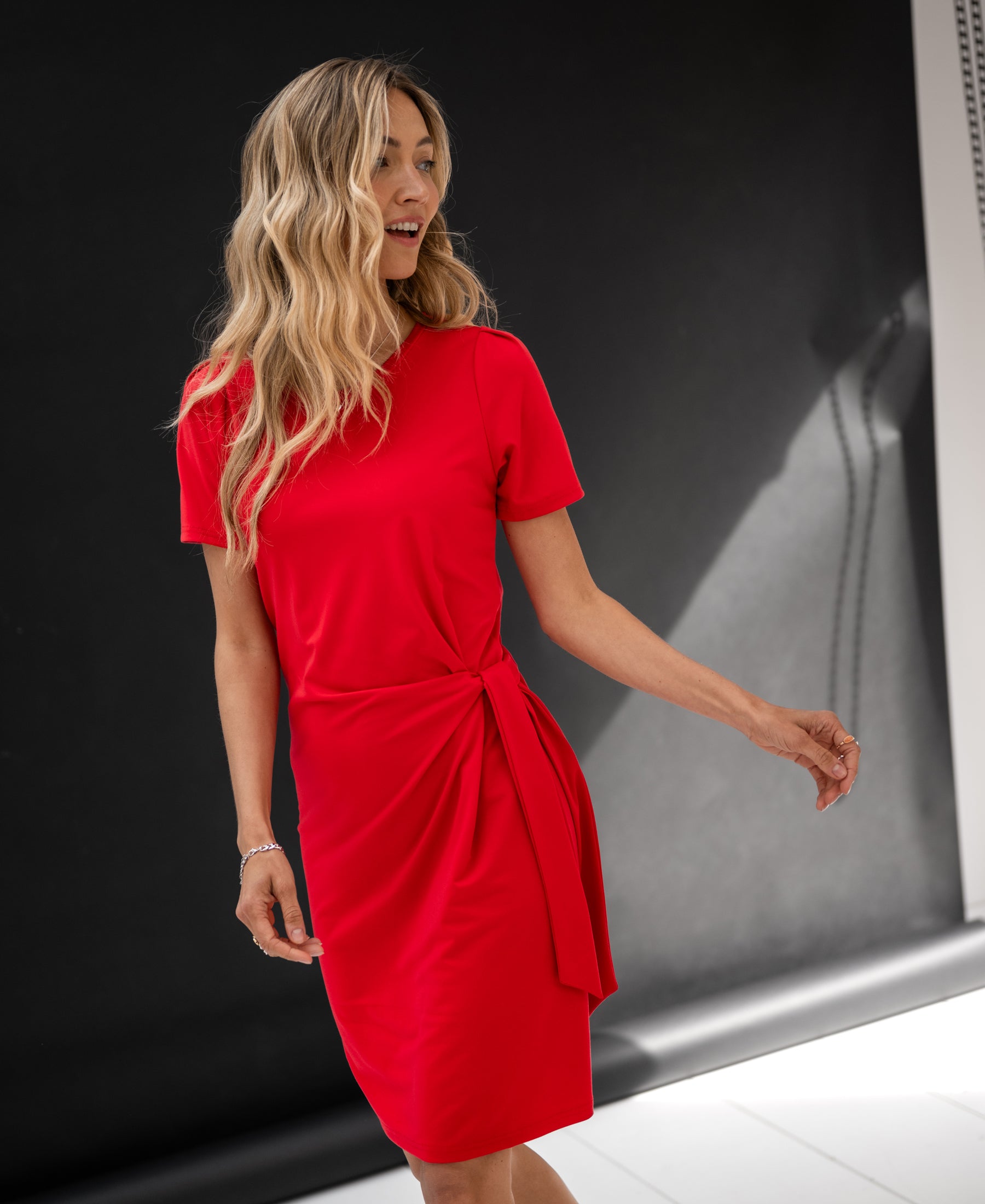 Red PLEIN PUBLIQUE LA FEE button dress shown against a dark, minimalist background.