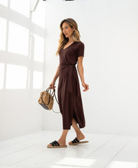 Woman wearing the LA FILICIA Cacao long dress by PLEIN PUBLIQUE in a bright white room.