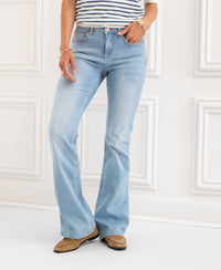 Person wearing bleached flare jeans indoors against a white wall.