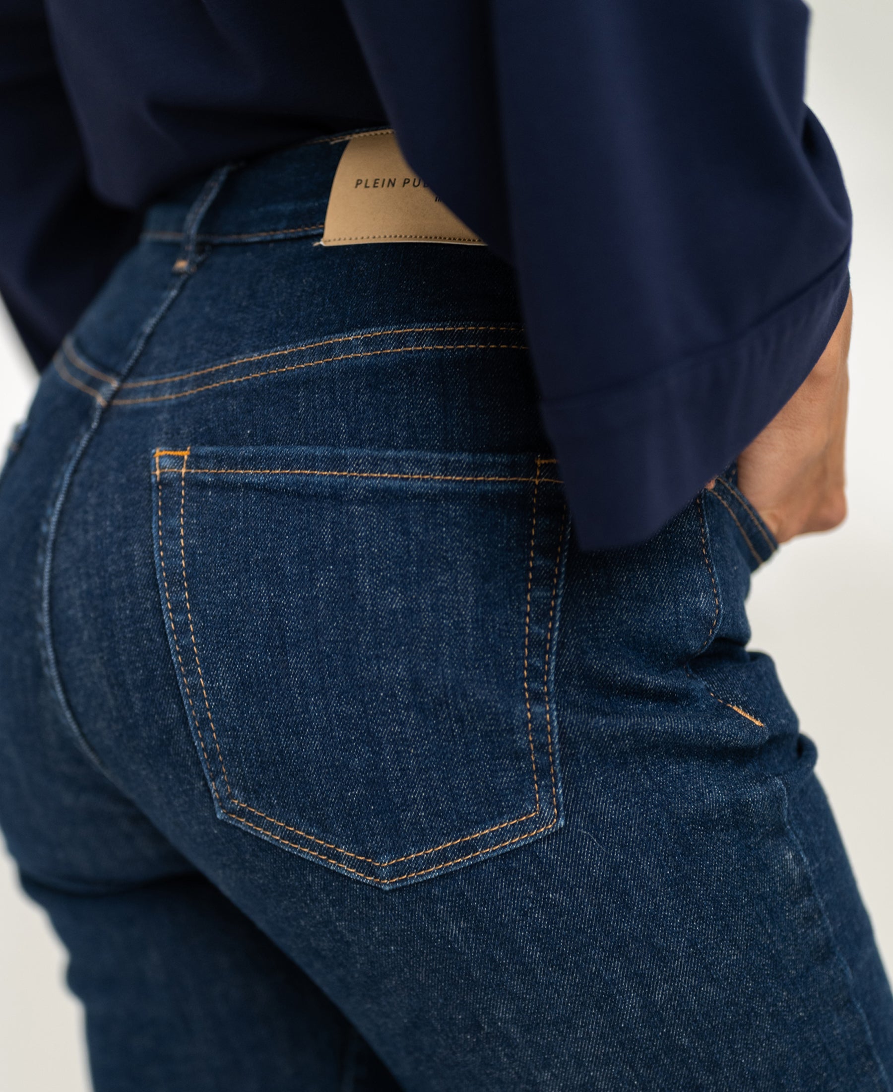 Woman wearing rinse wash flare jeans with one hand in the back pocket.