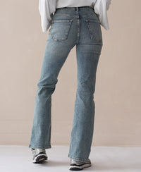 Flared vintage wash jeans shown from the back on a beige background.