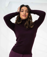 Woman wearing an aubergine Merino wool turtleneck sweater, shown against a white background.