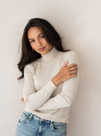 Woman wearing PLEIN PUBLIQUE Merino turtleneck sweater LA FORTE in beige, shown against a light wall.