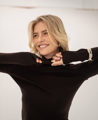 A woman wears a PLEIN PUBLIQUE Merino wool turtleneck sweater in pure chocolate brown.
