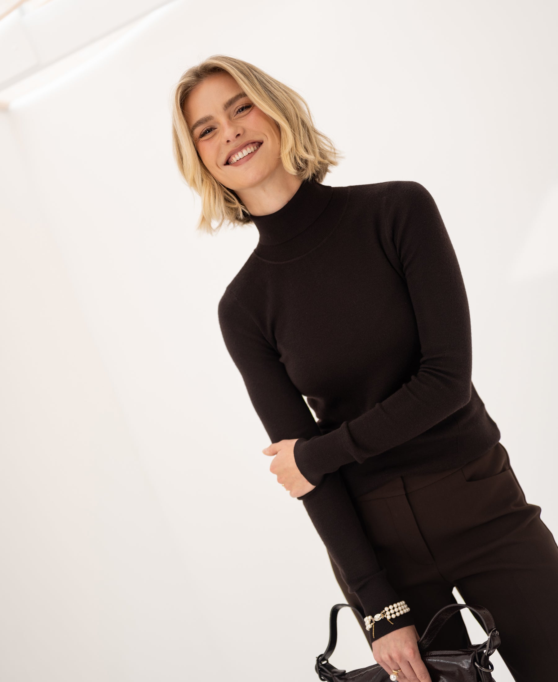 Woman wearing a pure chocolate brown merino wool turtleneck sweater.