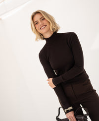 Woman wearing a pure chocolate brown merino wool turtleneck sweater.
