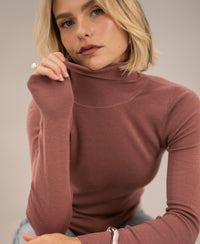 Dusty pink merino wool turtleneck sweater, shown from the front.
