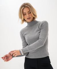 Woman wearing PLEIN PUBLIQUE Merino turtleneck sweater LA FORTE in feather grey adjusts her sleeve.
