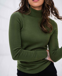 Woman wearing olive green merino wool turtleneck sweater, shown from shoulders to waist.
