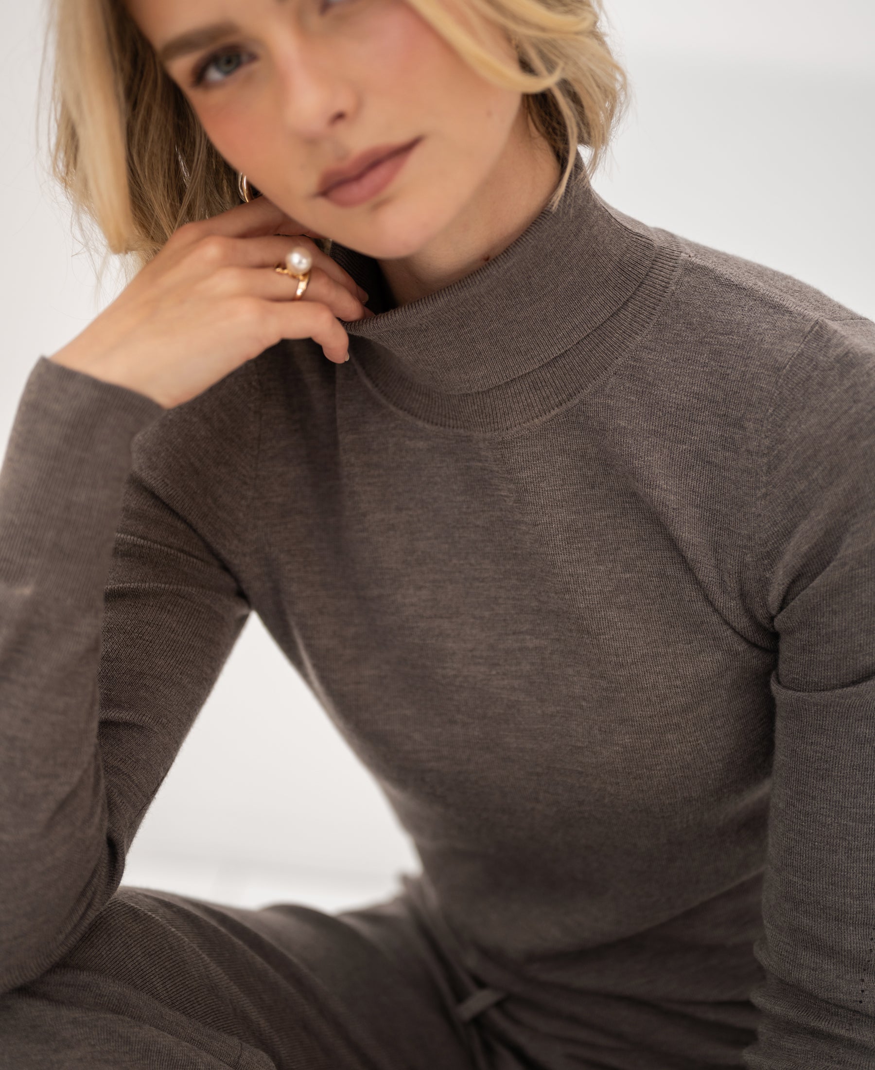 Merino wool turtleneck sweater in dark sand by PLEIN PUBLIQUE, shown on model.