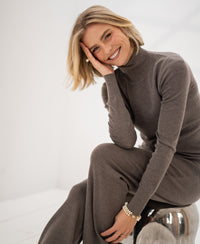 Merino wool turtleneck sweater in dark sand, shown in a minimal setting.
