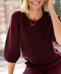 Woman wearing a PLEIN PUBLIQUE raspberry red sweater.
