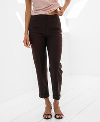 Woman wearing brown cropped pants on a white background.