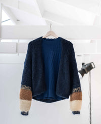 The PLEIN PUBLIQUE fluffy vest in dark blue with stripes hangs in a bright, modern room.
