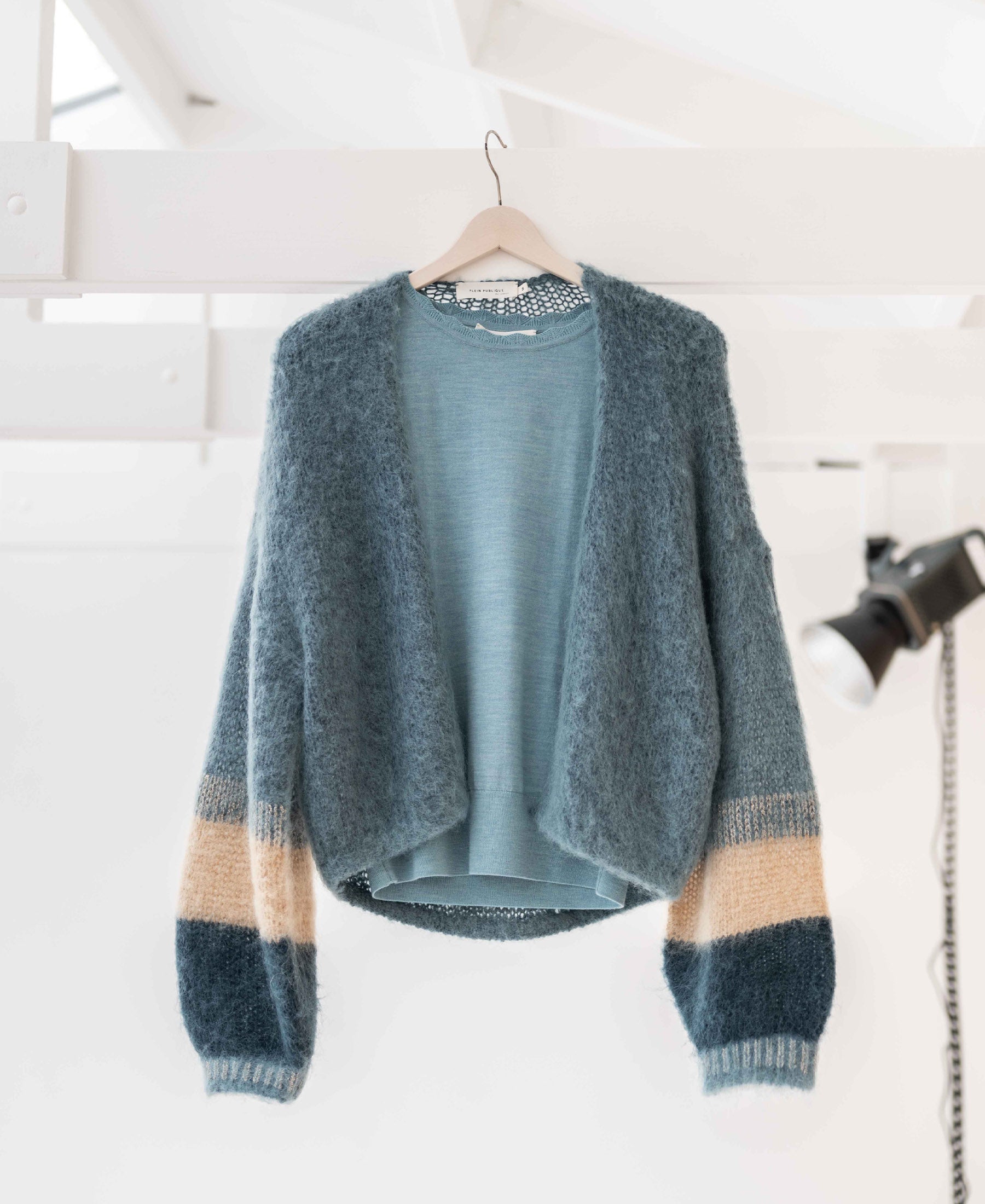 Mistgreen fluffy vest by PLEIN PUBLIQUE on a hanger.