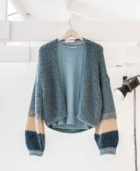 Mistgreen fluffy vest by PLEIN PUBLIQUE on a hanger.