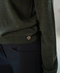 Close-up of a Merino wool LA GIGI sweater in bottlegreen with a heart charm.