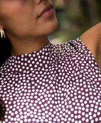 Woman wearing PLEIN PUBLIQUE polka dot blouse LA GIVERNY in wine-ivory, blurred background.