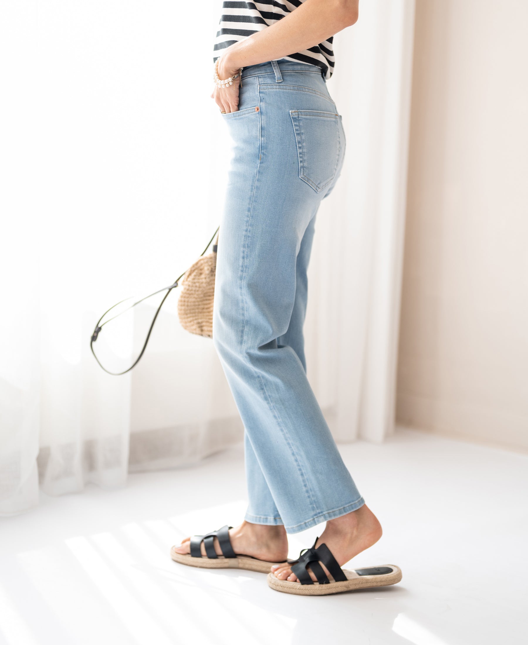Woman wearing bleached cropped jeans by PLEIN PUBLIQUE, in a bright room.