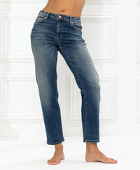 Cropped blue vintage jeans shown from shoulders down against a white wall.