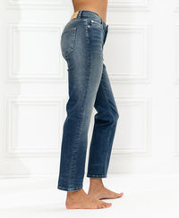 Cropped blue vintage jeans shown in profile against a white wall.