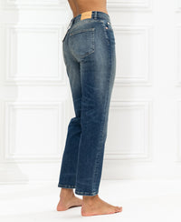 Blue vintage cropped jeans by Plein Publique, side view against a white wall.