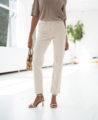 Woman wearing cream cropped jeans in a minimalist room.