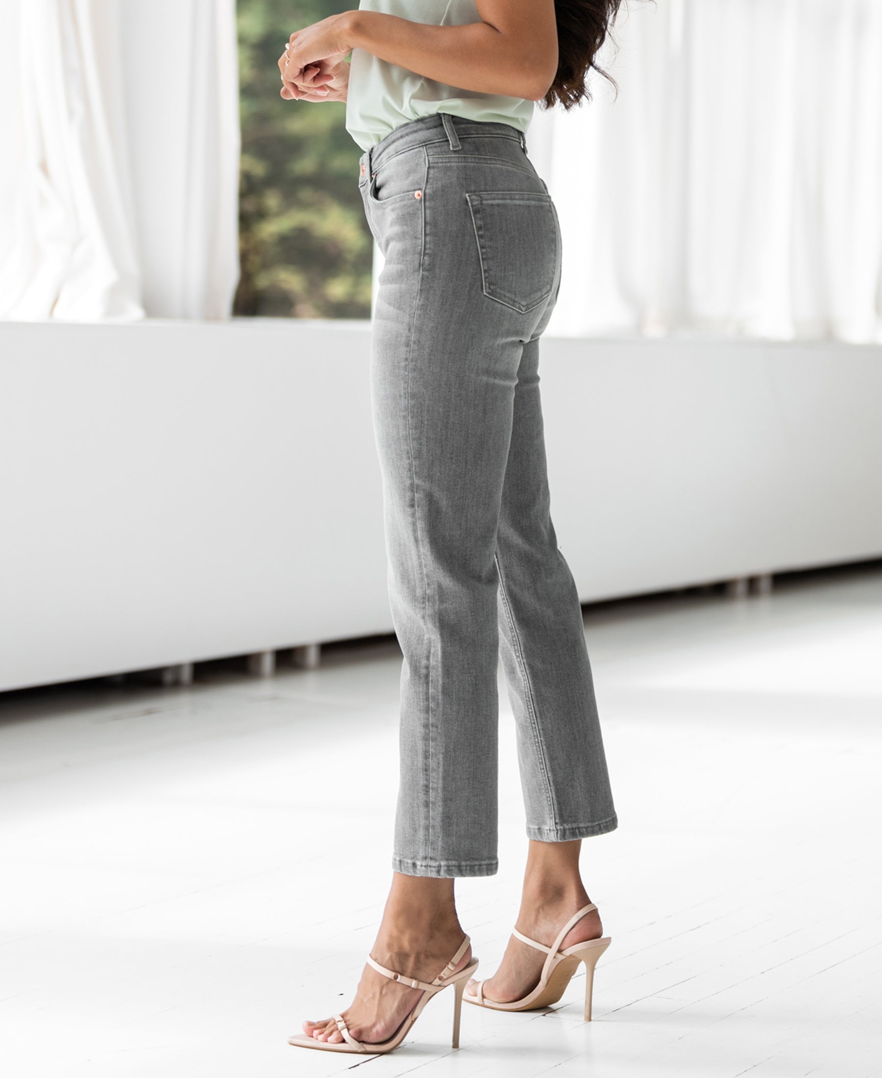 Grey stonewash cropped jeans in a straight-leg fit, shown near a bright indoor window.