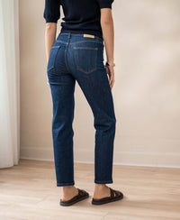 Back view of cropped blue jeans in rinsewash on light wooden floor.