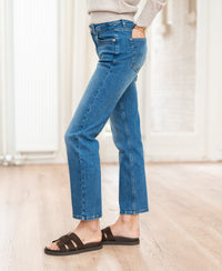 Person wearing cropped stonewash jeans indoors on a wood floor.