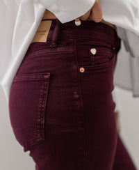 Close-up of cropped wine-colored jeans, showing pocket and waistband detail.